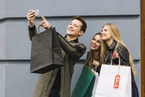 smiling-man-taking-selfie-with-his-female-friend-holding-shopping-bags